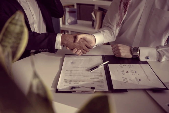 two people shaking hands over a piece of paper